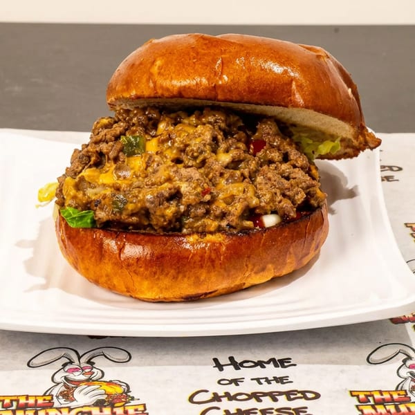A hearty chopped cheese sandwich on a brioche bun, served on a white plate.